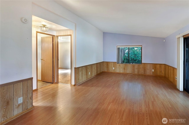 spare room with wooden walls, wood finished floors, and wainscoting