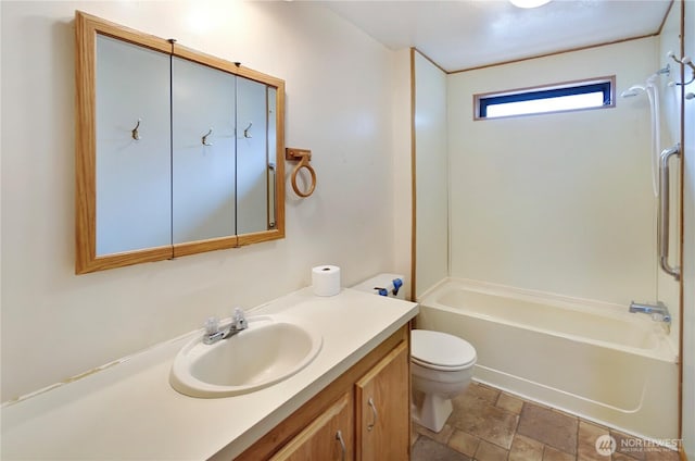 bathroom with stone finish floor, tub / shower combination, vanity, and toilet