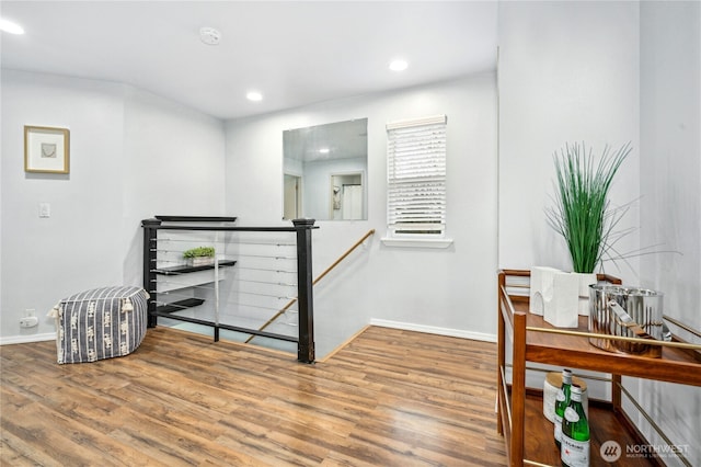 interior space featuring an upstairs landing, a baseboard heating unit, wood finished floors, recessed lighting, and baseboards