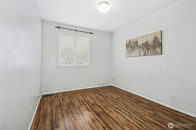 spare room featuring baseboards and wood finished floors