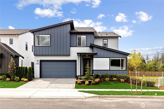 view of front of home with concrete driveway, an attached garage, fence, board and batten siding, and a front yard