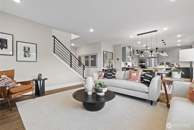 living room featuring recessed lighting, wood finished floors, baseboards, and stairs