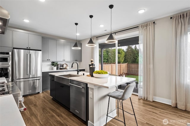 kitchen featuring appliances with stainless steel finishes, dark wood finished floors, light countertops, and a sink