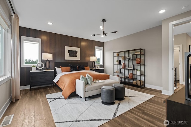 bedroom featuring recessed lighting, visible vents, wooden walls, wood finished floors, and baseboards