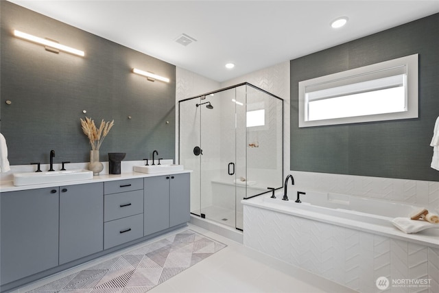 bathroom featuring a garden tub, double vanity, a sink, and a shower stall