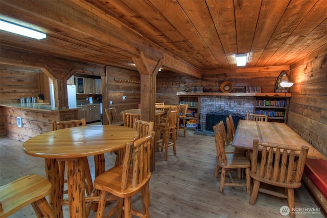 dining room with wood finished floors, wooden walls, wooden ceiling, and a fireplace