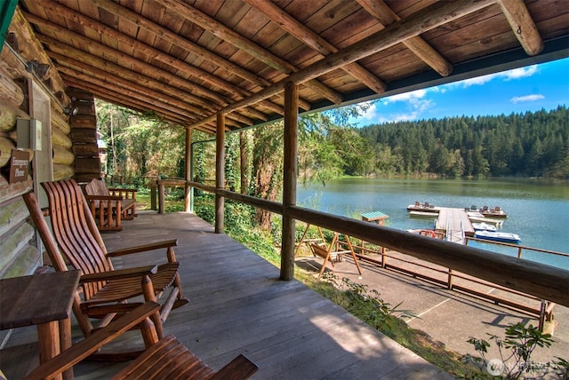 wooden terrace featuring a wooded view, a boat dock, and a water view