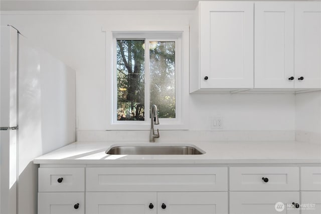 kitchen featuring light countertops, plenty of natural light, a sink, and white cabinetry