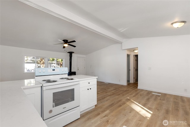 kitchen featuring white electric range oven, light countertops, lofted ceiling with beams, a wood stove, and white cabinets