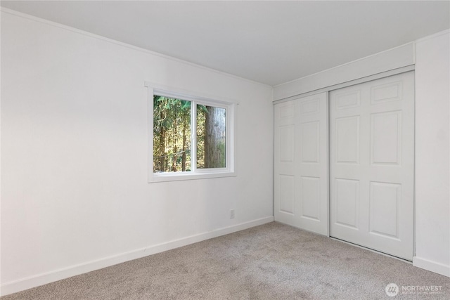 unfurnished bedroom with carpet floors, a closet, and baseboards