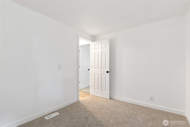 empty room featuring baseboards, visible vents, and light colored carpet