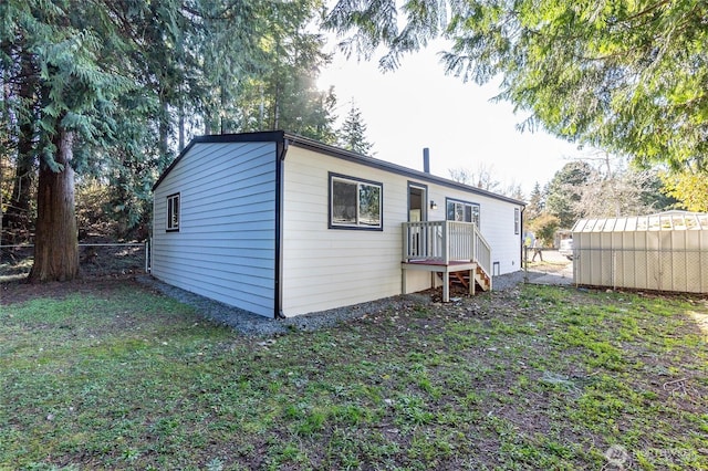 back of property featuring a yard, fence, and an outbuilding