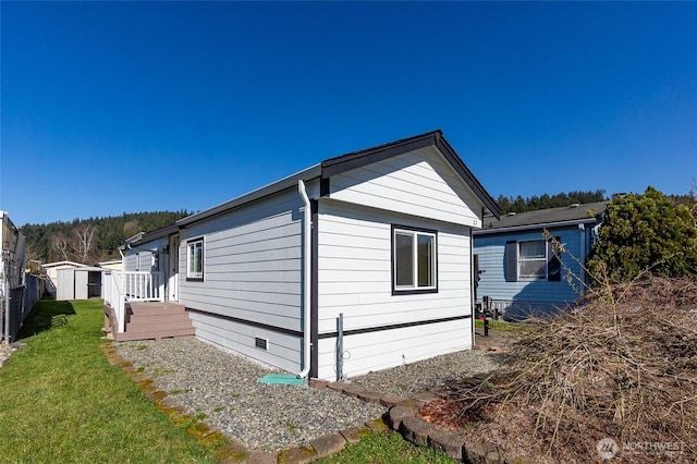 view of home's exterior with a storage shed, crawl space, fence, a yard, and an outdoor structure