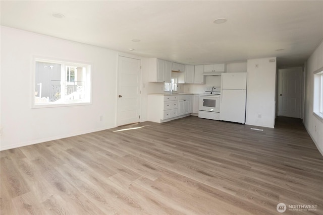 kitchen with a sink, wood finished floors, white cabinetry, electric stove, and freestanding refrigerator