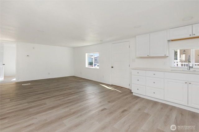 unfurnished living room with a sink and light wood finished floors