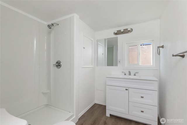 full bathroom with wood finished floors, a shower stall, vanity, and baseboards