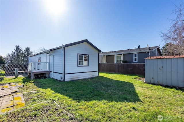 back of house with a shed, fence, a lawn, and an outbuilding