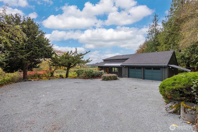 view of front of house with a garage, driveway, board and batten siding, and roof with shingles