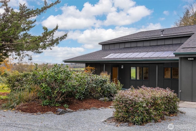 view of side of home featuring board and batten siding and roof with shingles