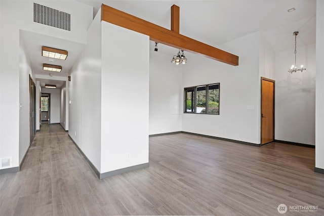 interior space with high vaulted ceiling, visible vents, a chandelier, and wood finished floors