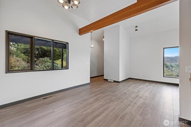 spare room with beam ceiling, wood finished floors, visible vents, and baseboards