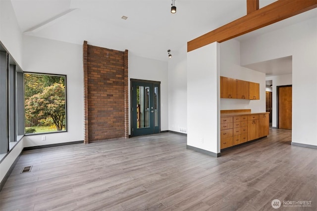 unfurnished living room featuring light wood-type flooring, visible vents, and baseboards