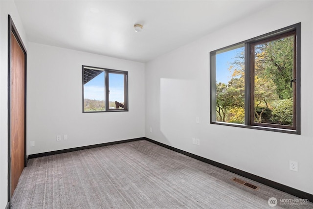 carpeted spare room with baseboards and visible vents