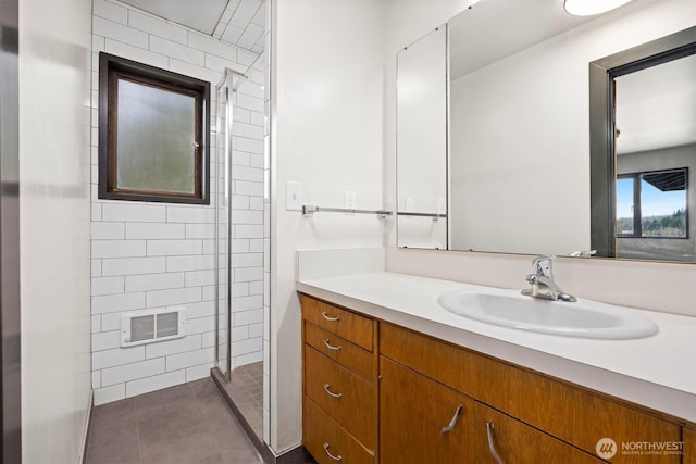 bathroom with tile patterned floors, visible vents, a tile shower, and vanity