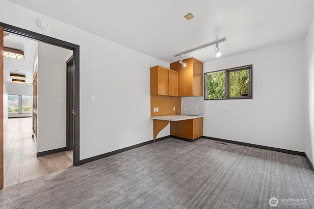 interior space featuring baseboards, light countertops, carpet floors, and brown cabinets