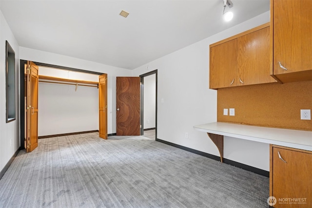 interior space with light colored carpet, baseboards, and built in study area