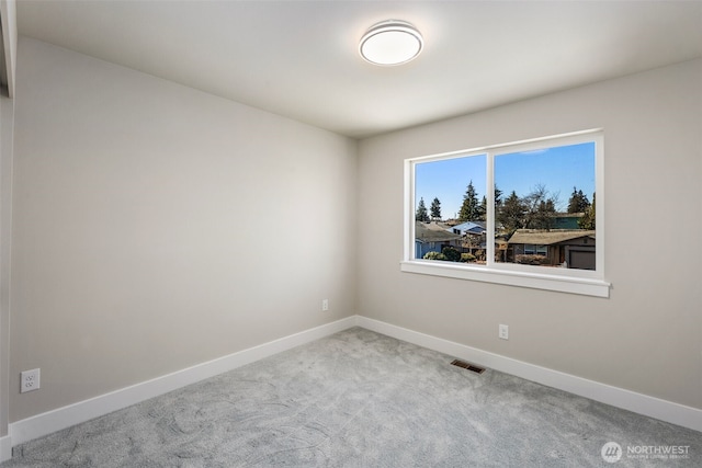 carpeted spare room featuring visible vents and baseboards