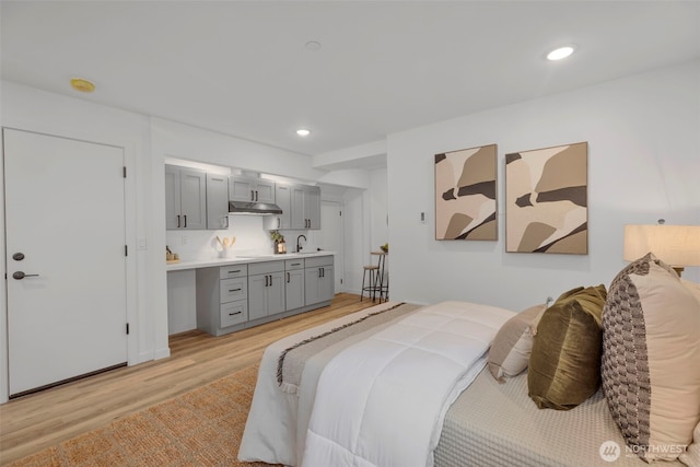 bedroom featuring recessed lighting, light wood-type flooring, and a sink