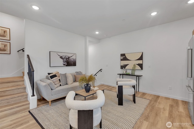 living room featuring recessed lighting, light wood-style flooring, stairs, and baseboards