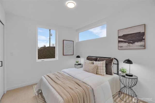 bedroom with baseboards and light carpet