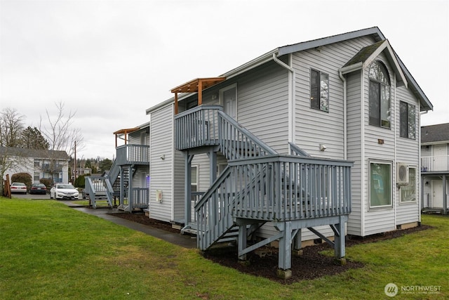 rear view of house featuring stairway, a lawn, and a wooden deck