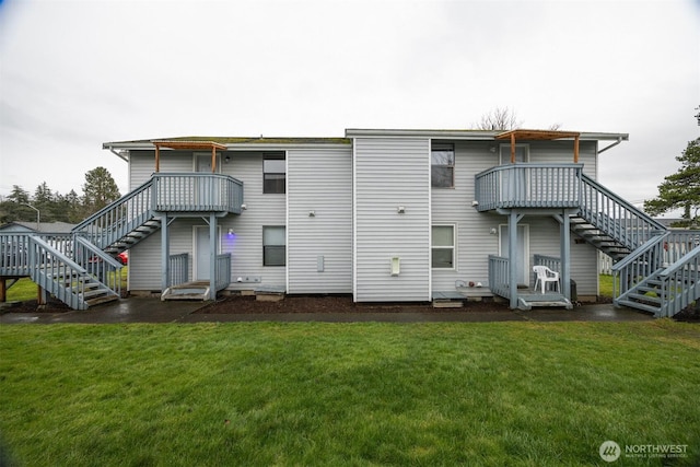 rear view of property featuring stairway and a lawn