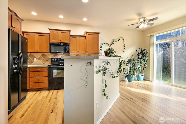 kitchen featuring black appliances, tasteful backsplash, brown cabinets, and a wealth of natural light