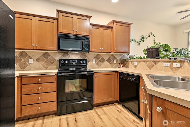 kitchen with black appliances, light wood-style flooring, a sink, and light countertops