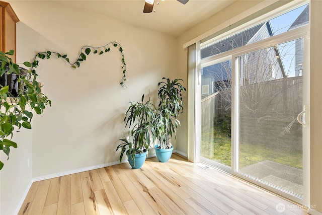 interior space with ceiling fan, wood finished floors, and baseboards