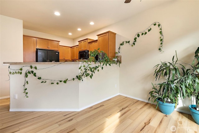 kitchen featuring light wood-style flooring, recessed lighting, baseboards, black appliances, and brown cabinetry