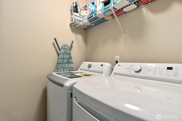 laundry area featuring laundry area, a textured wall, and washer and clothes dryer