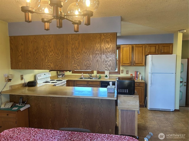 kitchen with brown cabinetry, an inviting chandelier, light countertops, black appliances, and a sink