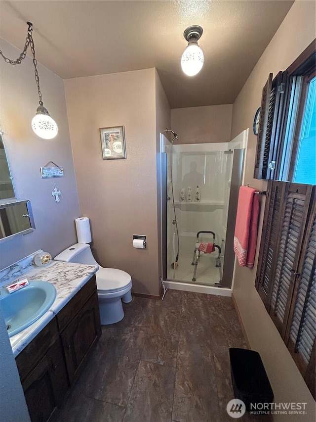 full bathroom with a stall shower, vanity, toilet, and baseboards