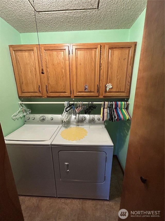 washroom with cabinet space, tile patterned flooring, washer and clothes dryer, and a textured ceiling