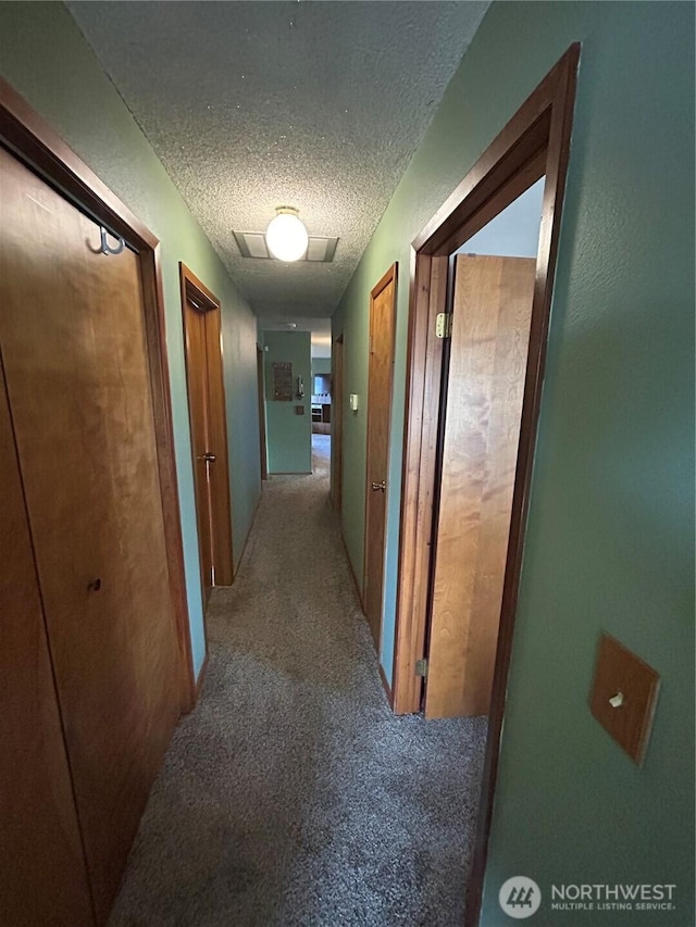 hallway featuring a textured ceiling and light colored carpet