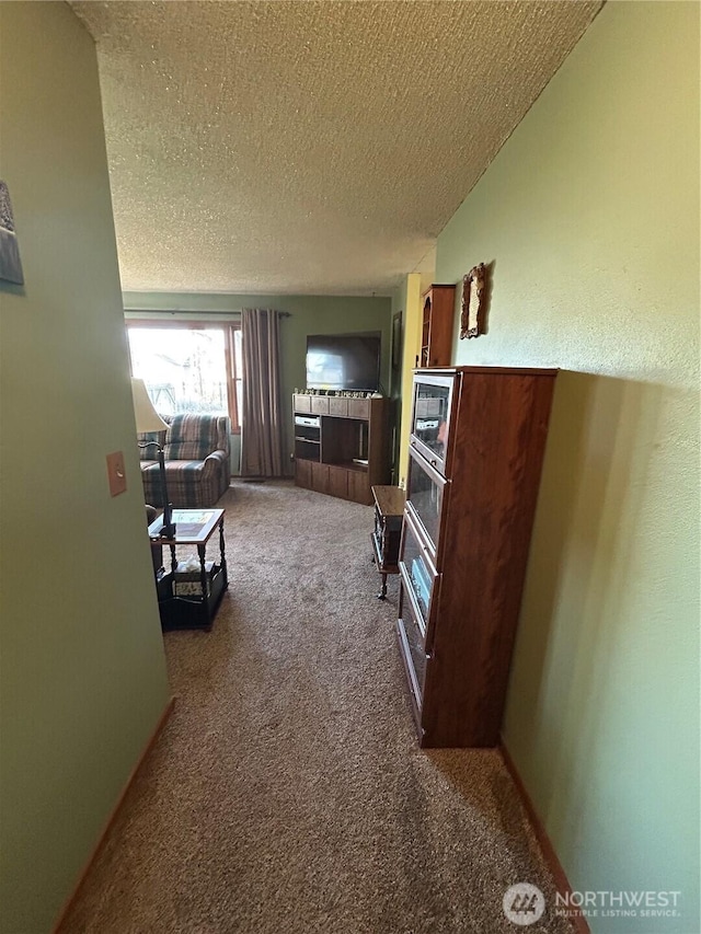 living room with a textured ceiling, carpet flooring, and baseboards