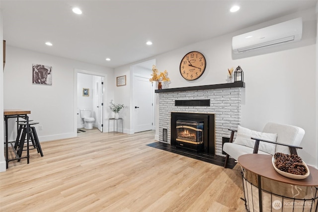 living area with a wall mounted air conditioner, wood finished floors, and recessed lighting