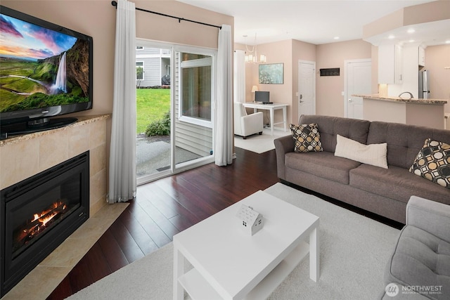 living area with a fireplace, dark wood finished floors, a notable chandelier, and recessed lighting