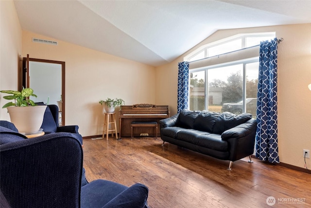 living area featuring visible vents, vaulted ceiling, baseboards, and wood finished floors