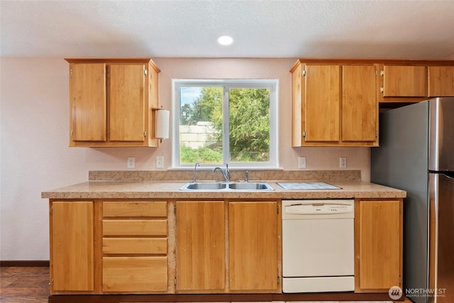 kitchen with freestanding refrigerator, white dishwasher, light countertops, a sink, and recessed lighting